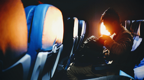 Мужчина проверяет свою сумку в самолете.
